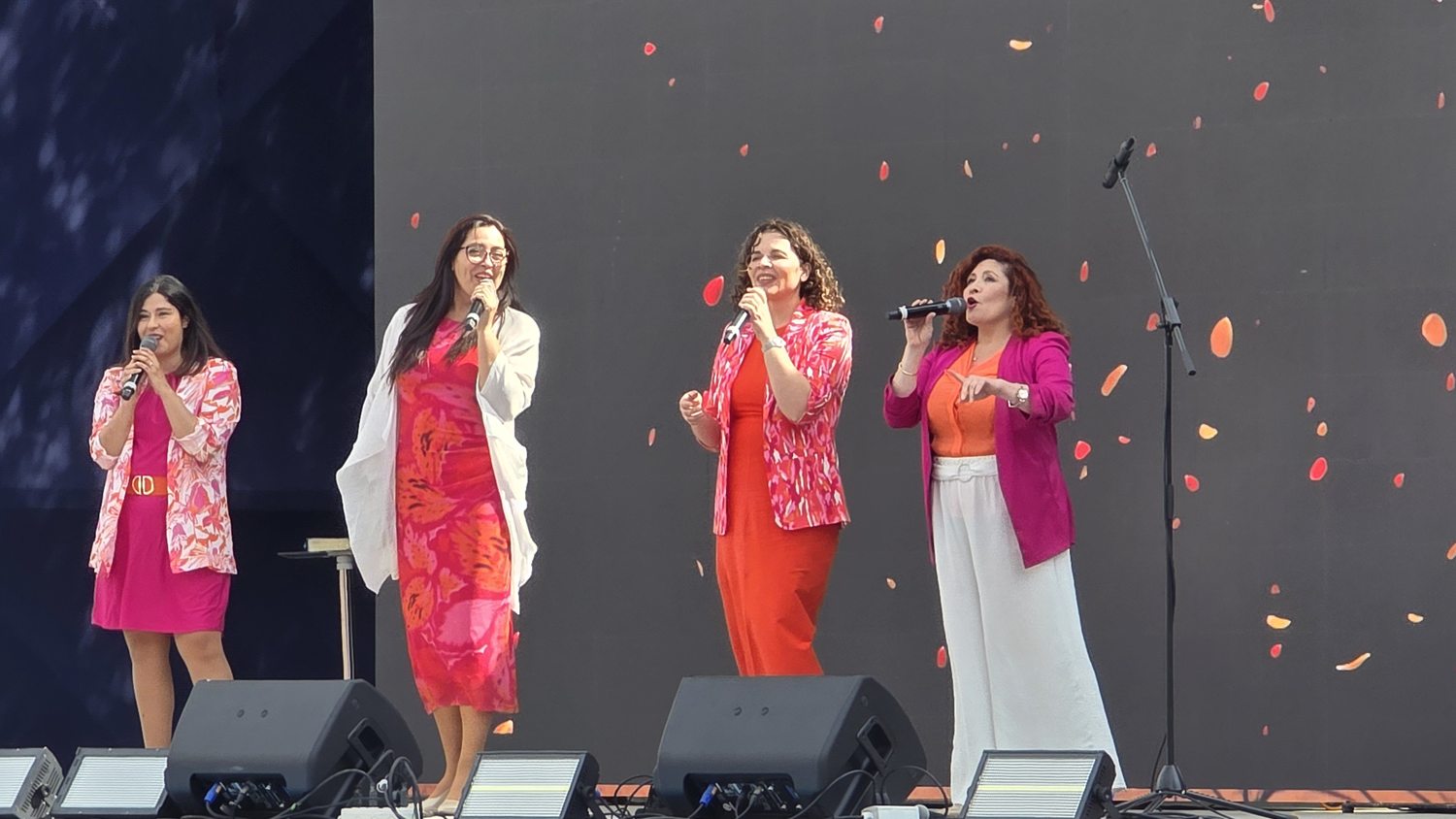 Dúnamis cantando en el escenario con papel picado en la pantalla